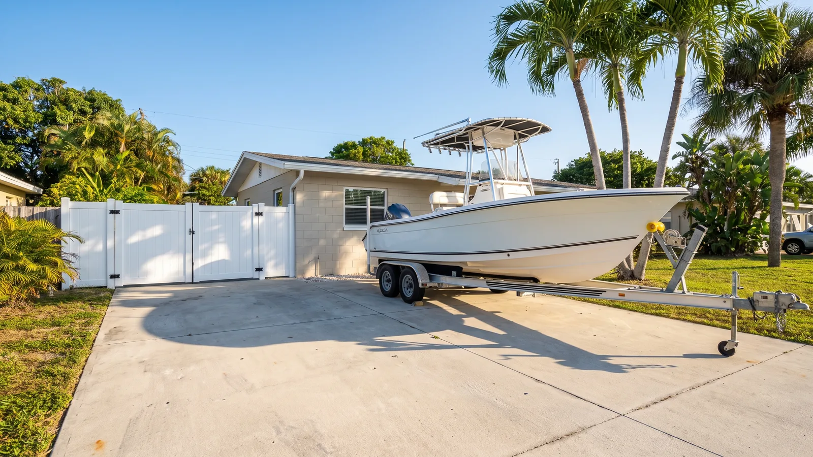 Reinforced concrete boat pad beside a house with a boat on a trailer parked on it